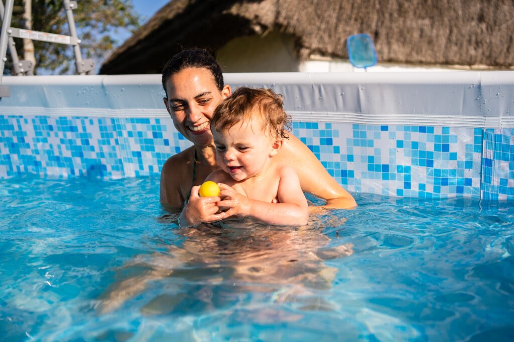 Mother and baby playing with a ball inside a pool
