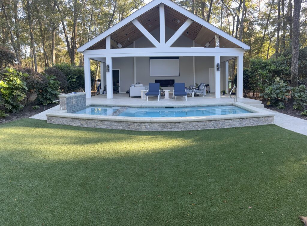 Rectangular pool with low stone-and-concrete wall. A pavilion covers the concrete patio.