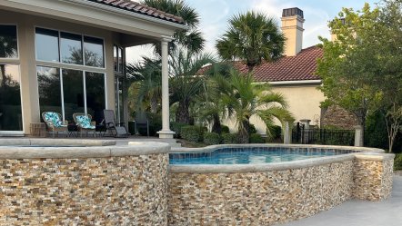 Pool with attached hot tub and travertine walls.
