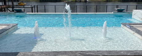 A set of three fountains near the edge of a pool.