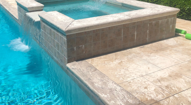 An attached spa next to a deck with large flagstones made of concrete textured to look like stone.
