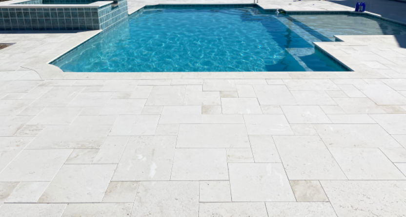 A inground rectangular pool with an attached spa. The surrounding patio is made of concrete stamped with a stone pattern.